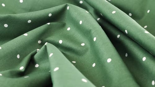 Top view of the soft folds of hooker's green with white polka dots cotton fabric rotated