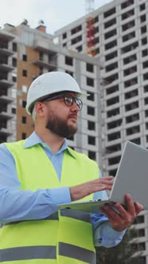 Vertical Screen Building Inspector Making Notes on Laptop at Construction Site