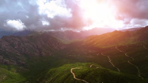 Scenic mountain landscape at sunset with winding trails and clouds