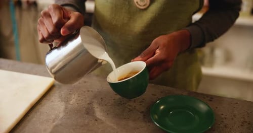Latte art, jug and barista with steam milk in cafe for coffee, espresso or cappuccino drink