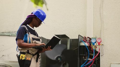 HVAC Technician Inspecting Air Conditioning Unit with Laptop