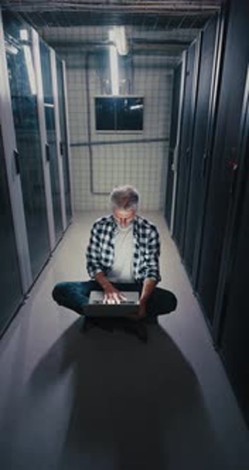 Mann benutzt Laptop im Serverraum