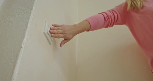 Hand turning off wall light switch indoors