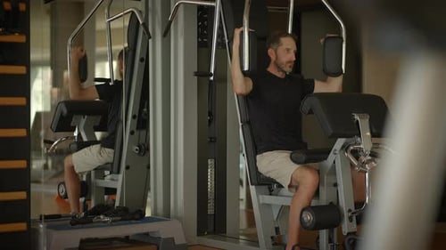 A Dedicated Man is Utilizing a Hightech Exercise Machine in a Modern Gym Environment