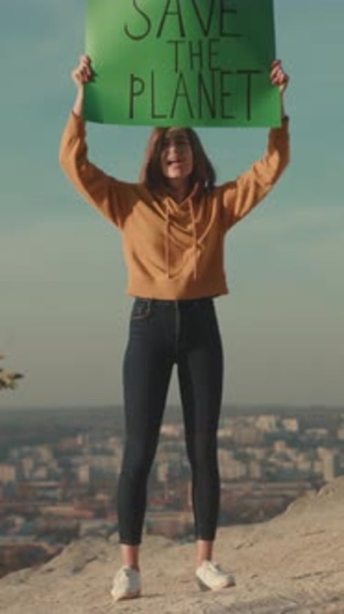 Young Woman Urges Climate Action Determined Young Woman in Hoodie Promotes Environmental Urgency at