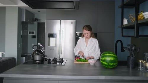 Caucasian Woman Making a Salad of Vegetables on Modern Kitchen Island Young Female Cuts the Greens