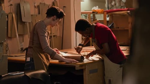 Young Multiethnic Artisans Cutting Leather Fabric Details in Workshop