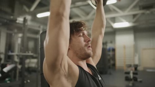Male Bodybuilder Doing Dumbbell Overhead Press Exercise in Gym