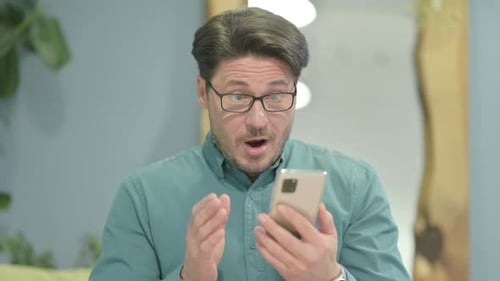 Excited Man Checks Phone and Celebrates Good News