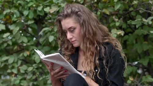 Closeup Portrait of Curios Young Gorgeous Woman Reading Book Sitting in Park Outdoors