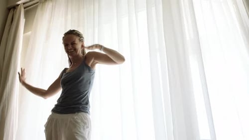 Woman Dancing Joyfully at Home by Window