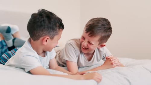 Children, laughing and conversation on bed, fun and silly jokes in discussion