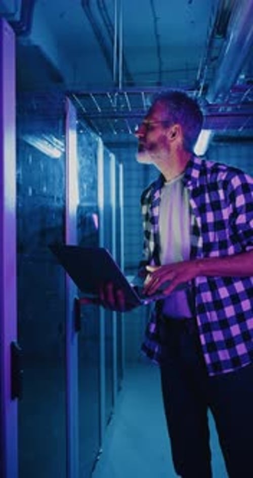 IT-Servertechniker mit Brille starrt auf das Neondisplay