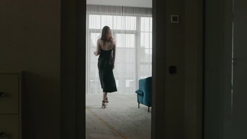 Elegant Woman Walks to Window with Wine Glass