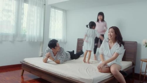 Happy Family Jumps on Bed in Bright Home