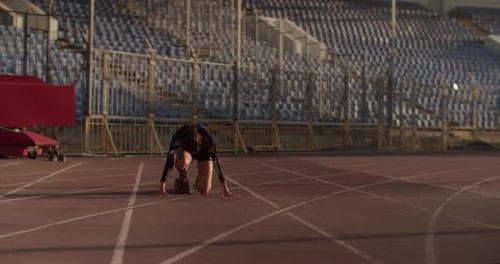 Athletic Female Sprinter at Starting Block in Stadium