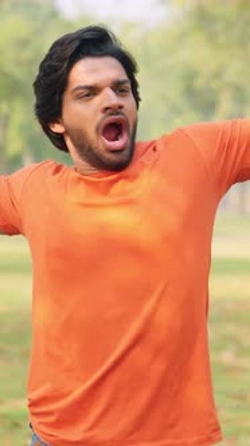 Young Adult Stretches and Yawns in Park