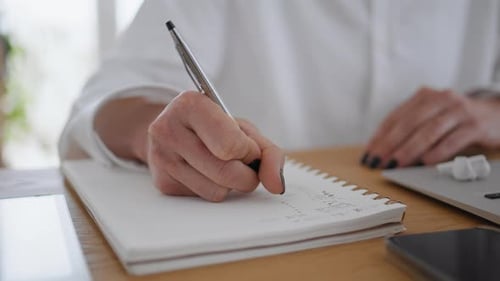 Woman Writes in Notebook at Desk