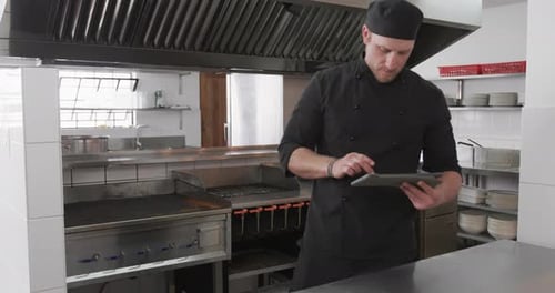 Caucasian male chef using tablet in kitchen, slow motion