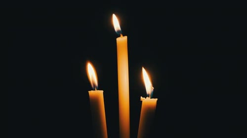 Three Yellow Candles Flickering in the Darkness