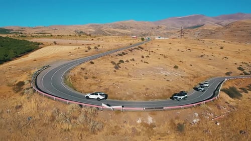 Cars Drive Along the Road Past the Deserted Hills Bird's Eye View