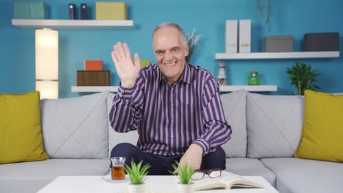 Cheerful Man Waving From Home on the Couch