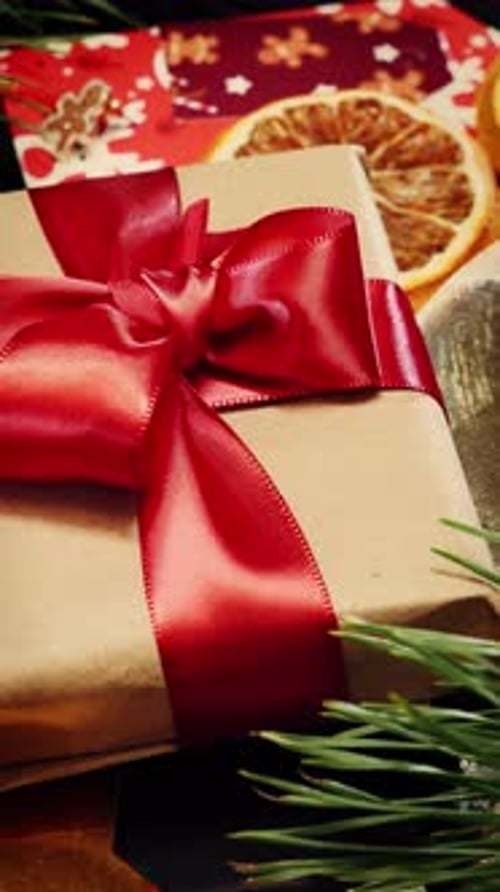 Wrapped with red ribbon gift and christmas decorations rotating. Vertical video