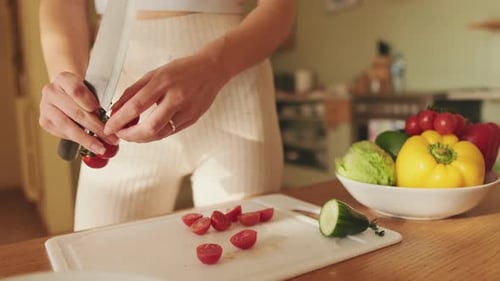 Close-up of young woman's hands cutting tomatoes making salad at home in the kitchen