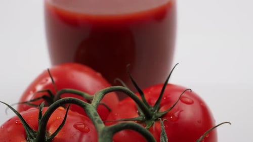 Frisch zubereiteter Tomatensaft und Tomaten auf weißem Hintergrund.