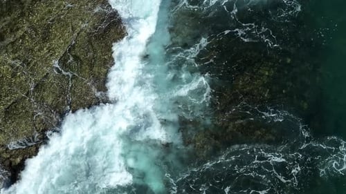 Rough ocean waves splashing against rocky shore.