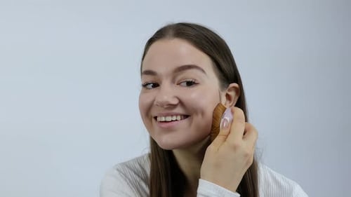 Smiling Woman Applying Makeup with a Brush