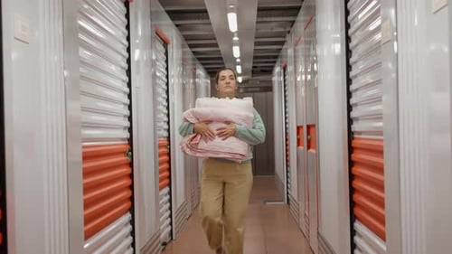 Femme avec ses affaires marchant dans une unité de self-stockage