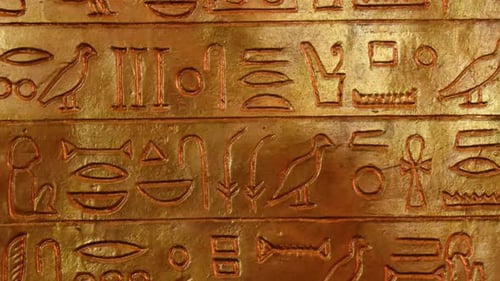 Hiéroglyphes étonnants gravés sur le mur doré de la tombe, vue de symboles anciens gravés sur plaque