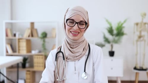 Confident Female Doctor in Modern Medical Office with Laptop