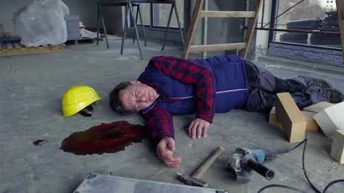Construction worker lying injured on floor near equipment