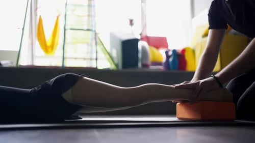 Close Up of Unrecognisable Coach Hands Holding Child Girl Legs During Stretching Strength Exercise