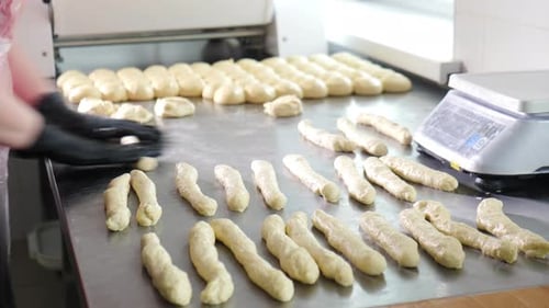 Baker Shaping Dough on Metal Table