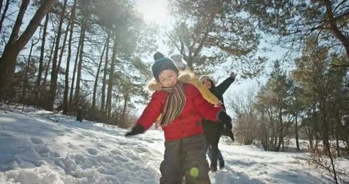 Eltern und Kinder spielen im Wald und gehen entlang des verschneiten Pfades