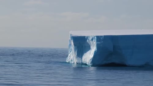 Massiver blauer Eisberg, der friedlich im tiefblauen Meer schwimmt