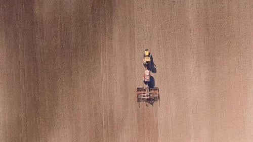 Aerial View Tractor Cuts Furrows in Farm Field for Sowing Farm Tractor with Rotary Harrow Plow