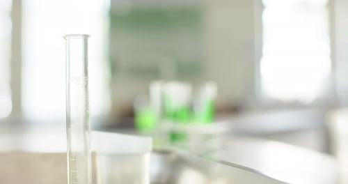 Le focus pull se déplace de la gauche vers le support de tubes à essai, révélant des solutions vert vif pour l'analyse