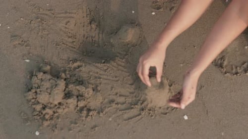 Zeitlupenaufnahme aus der Vogelperspektive von den Händen einer jungen Mutter und ihrer kleinen Tochter während ihres Sommers
