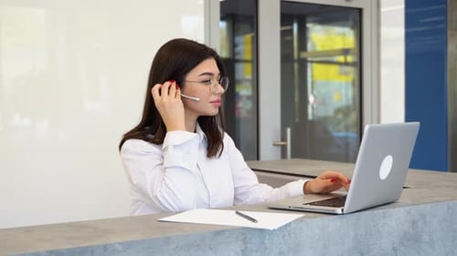 Woman Works on Laptop with Headset in Office