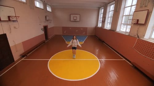 Young Girl Jumping Rope in Empty School Gymnasium