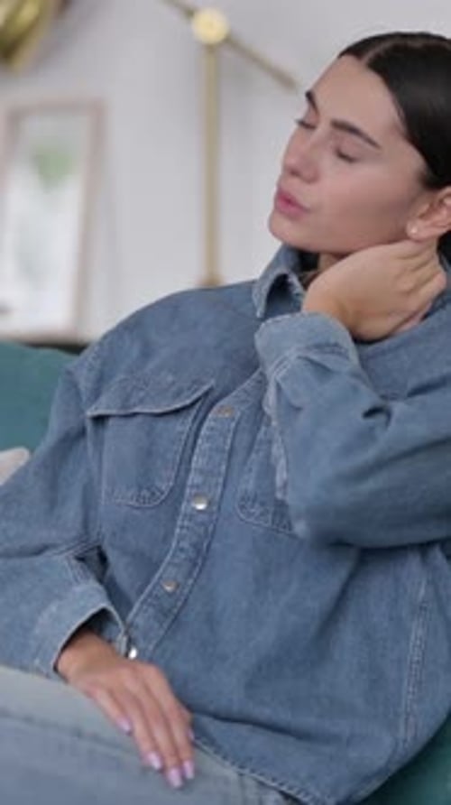 Young Woman Stretches Neck Indoors for Relaxation