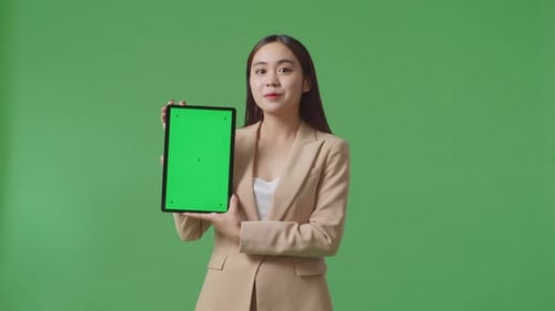 An Asian Business Woman Showing Tablet Green Screen On Green Screen Background In The Studio