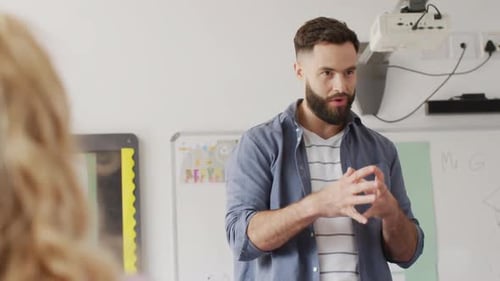 Diverse male teacher and schoolchildren at desks in school classroom