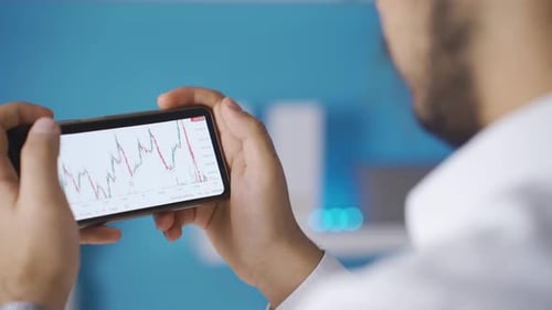 Vue rapprochée des graphiques boursiers et des cryptomonnaies depuis le téléphone.