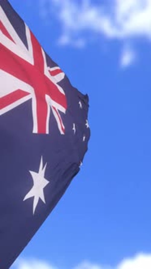 Australian Flag Waving in Wind Against Blue Sky