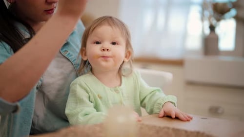 Mother Feeding Young Child at Kitchen Table